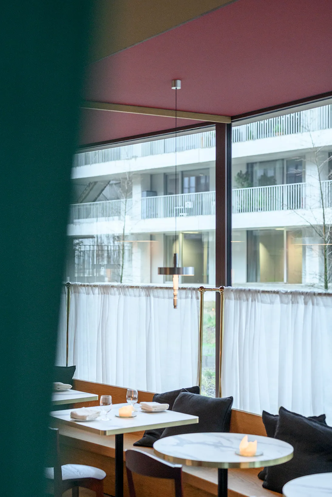Ronde marmeren tafels en eiken bank aan het raam van Bar Misera