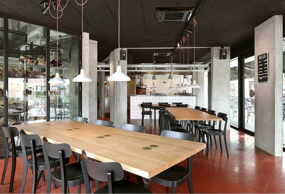 Lange beuken tafels in de zaal van Carcasse met grote ramen