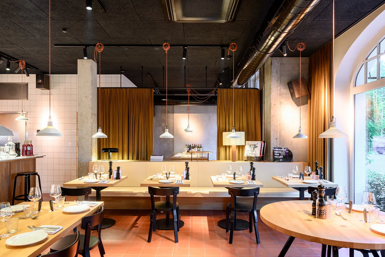 Restaurantzaal van Carcasse in Knokke met beuken tafels en rode tegelvloer, ontworpen door Studio Bjorn Verlinde