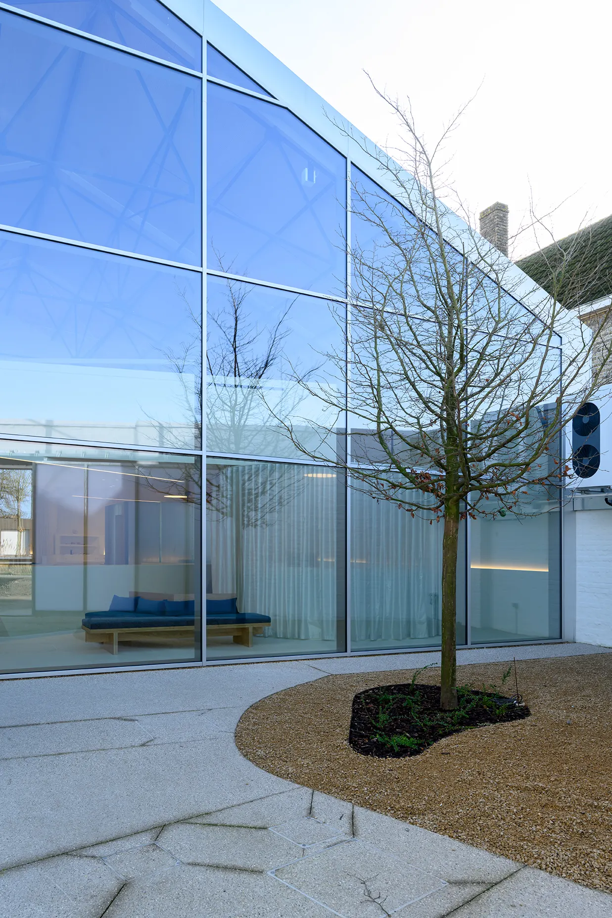 Patio met boom achter de glazen gevel van de praktijk