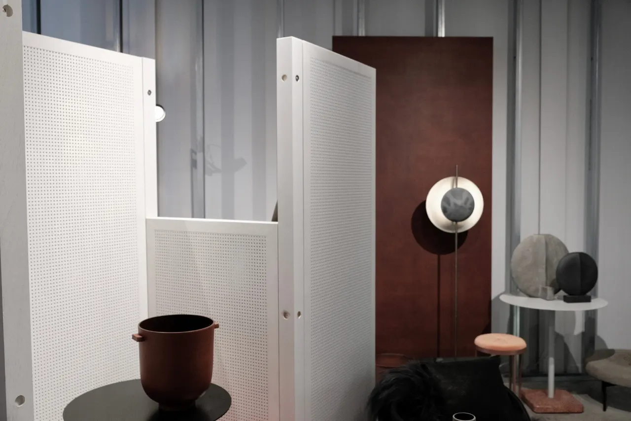 Geperforeerde witte panelen en roestbruin vlak met designobjecten in Domus+ Roeselare