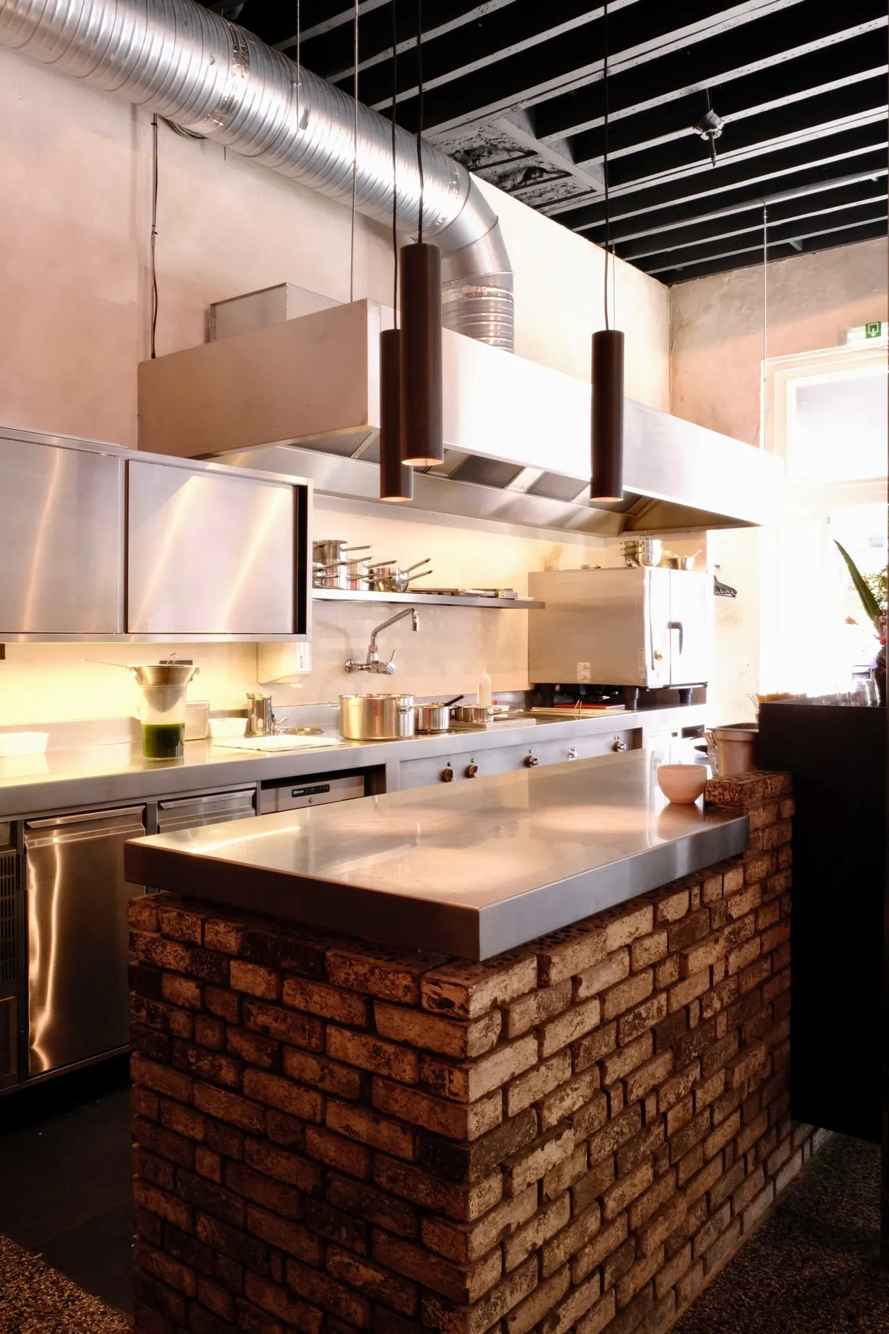 Bakstenen toog en open keuken met inox dampkap