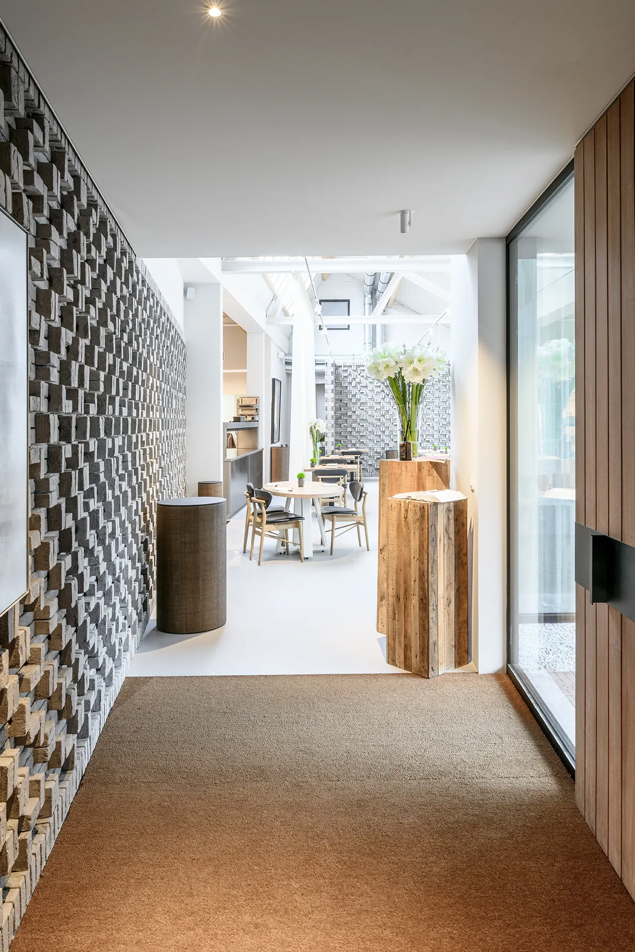 Gang met reliëfmetselwerk en houten deur naar de zaal