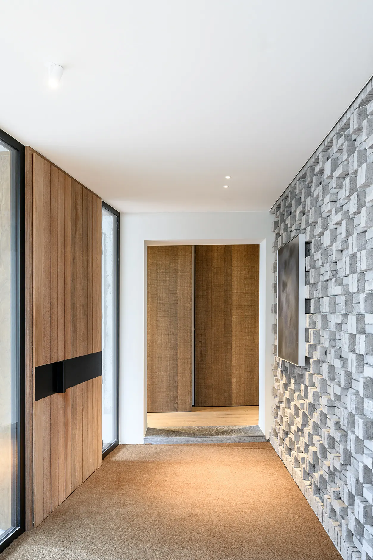 Inkom met houten deuren en grijze bakstenen wand