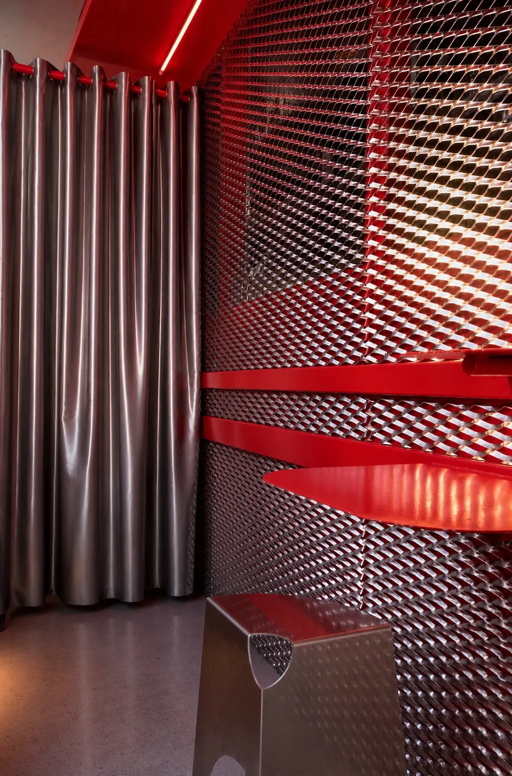 Geperforeerde metalen wand met rood licht en zilveren gordijn in Mosh!