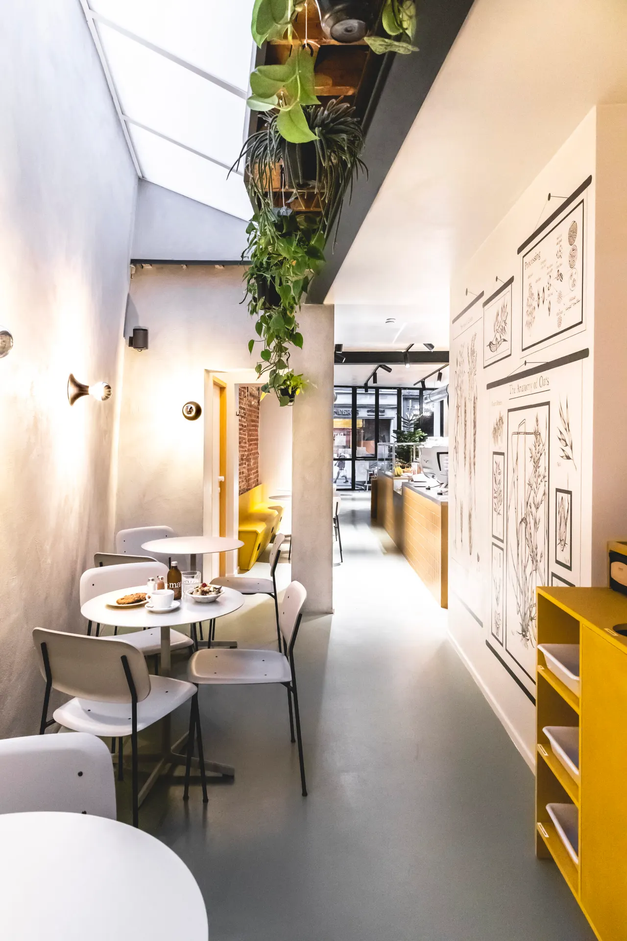 Smalle zaal met gele kast, tafeltjes en planten bij Oatsdaylong in Gent