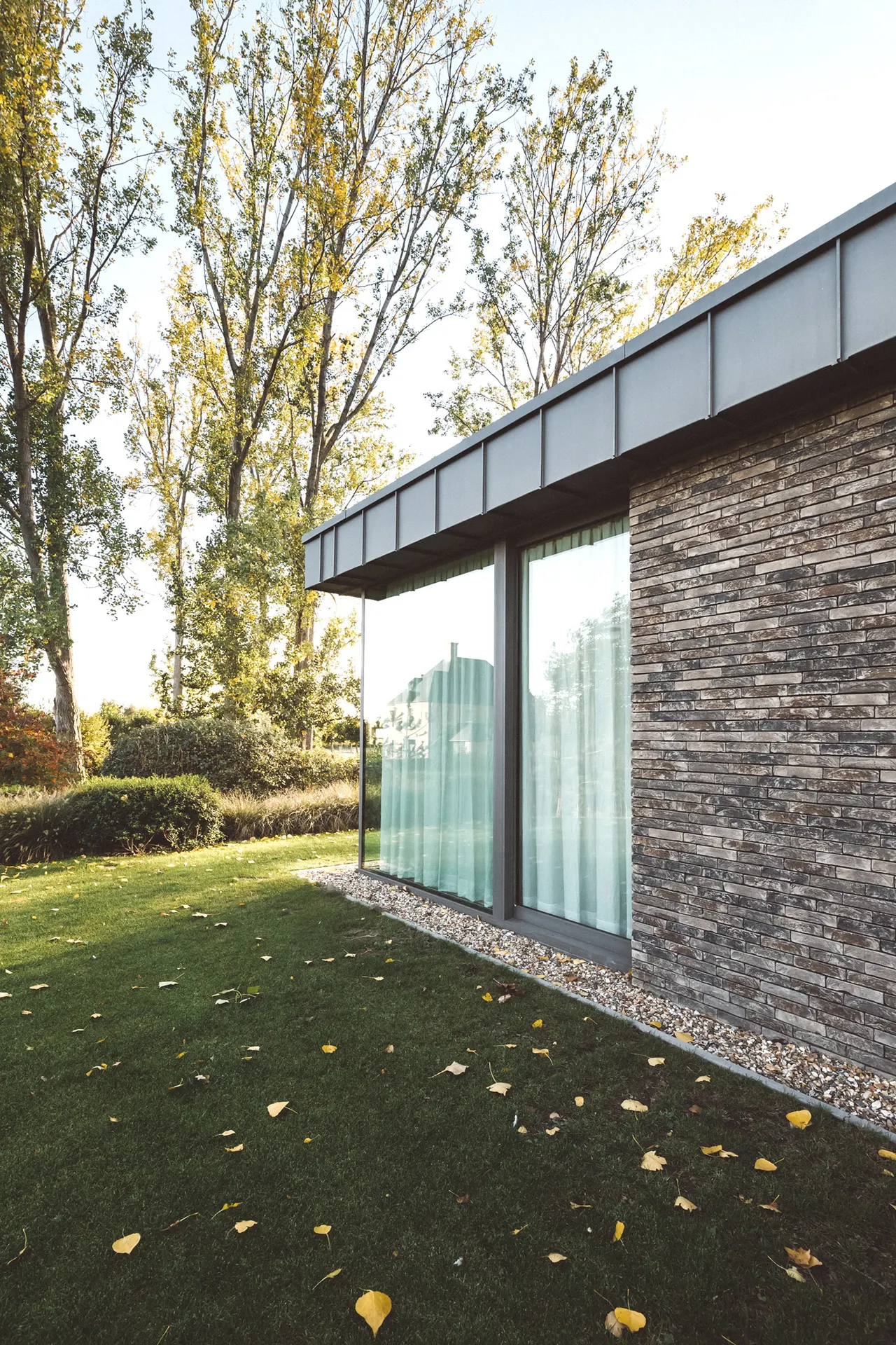Buitenzicht op de woning tussen herfstbomen