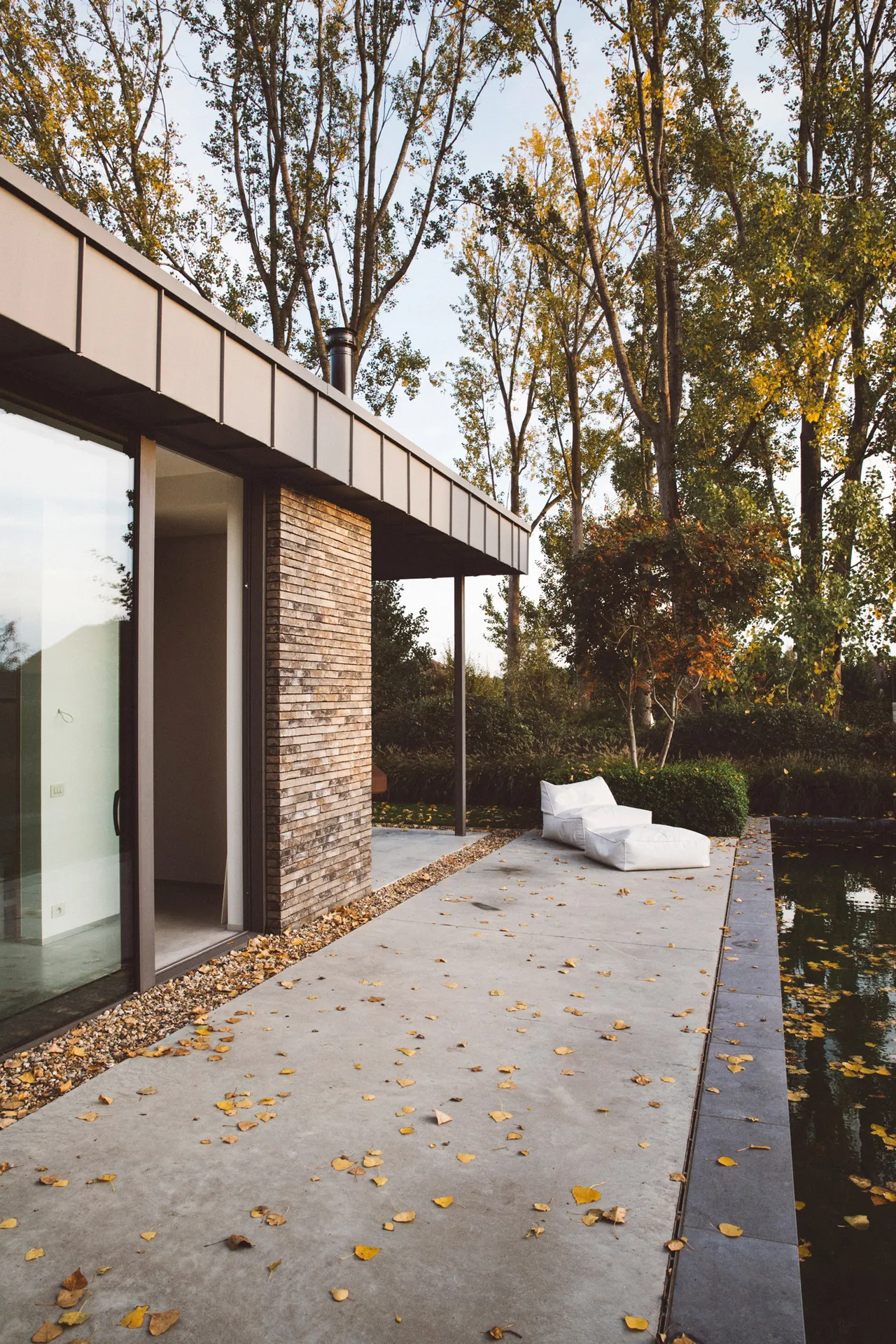 Overdekt terras langs de natuurstenen gevel met herfstbladeren