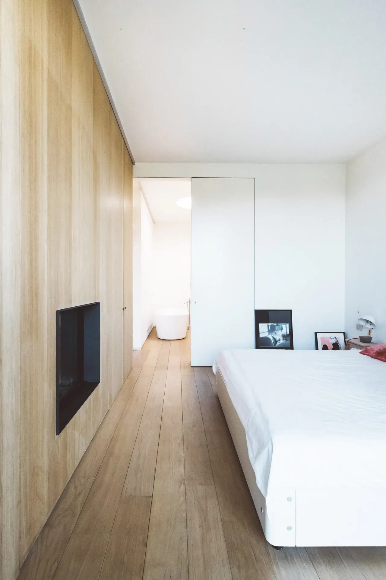 Slaapkamer met lichte houten wand en wit bed