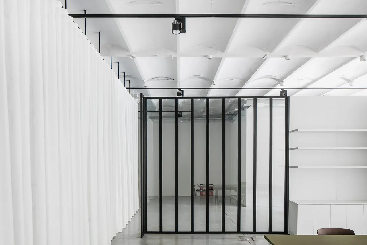 Glazen vergaderruimte tussen linnen voiles in de showroom van Six Edges