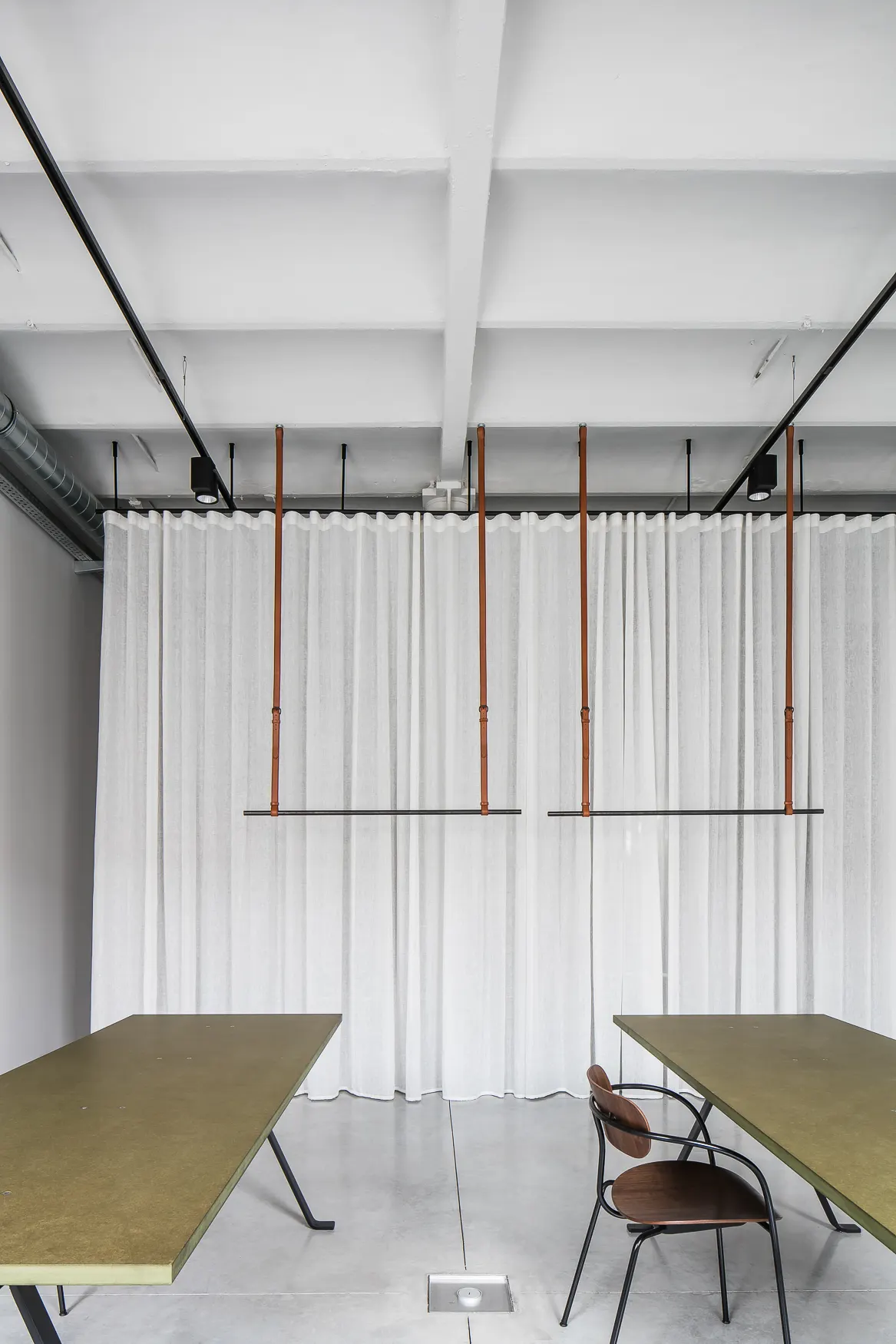Twee tafels onder kledingrekken in de showroom