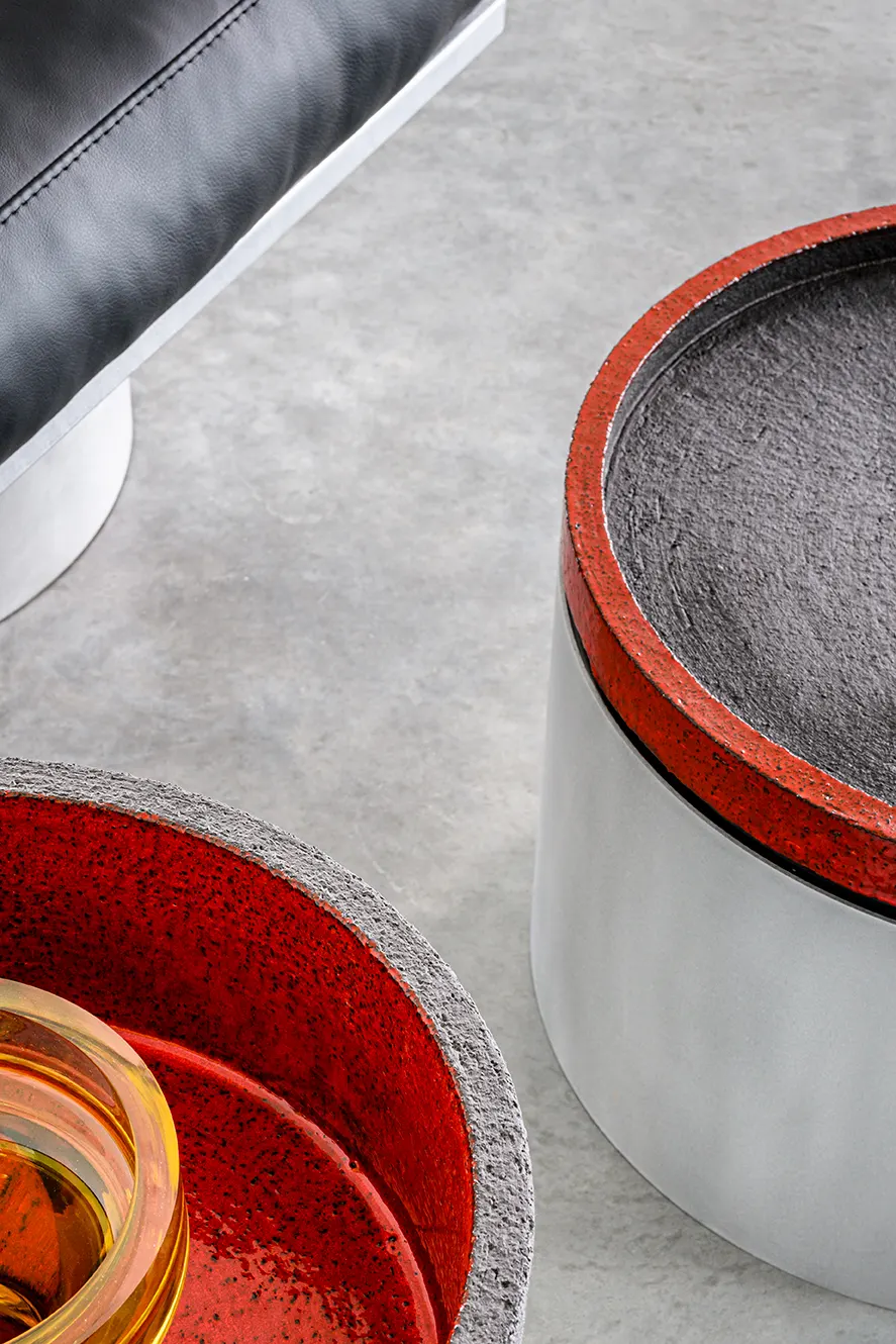 Aluminium bijzettafel met rood gelakte bovenkant naast een lederen zetel, uit de reeks Mixture