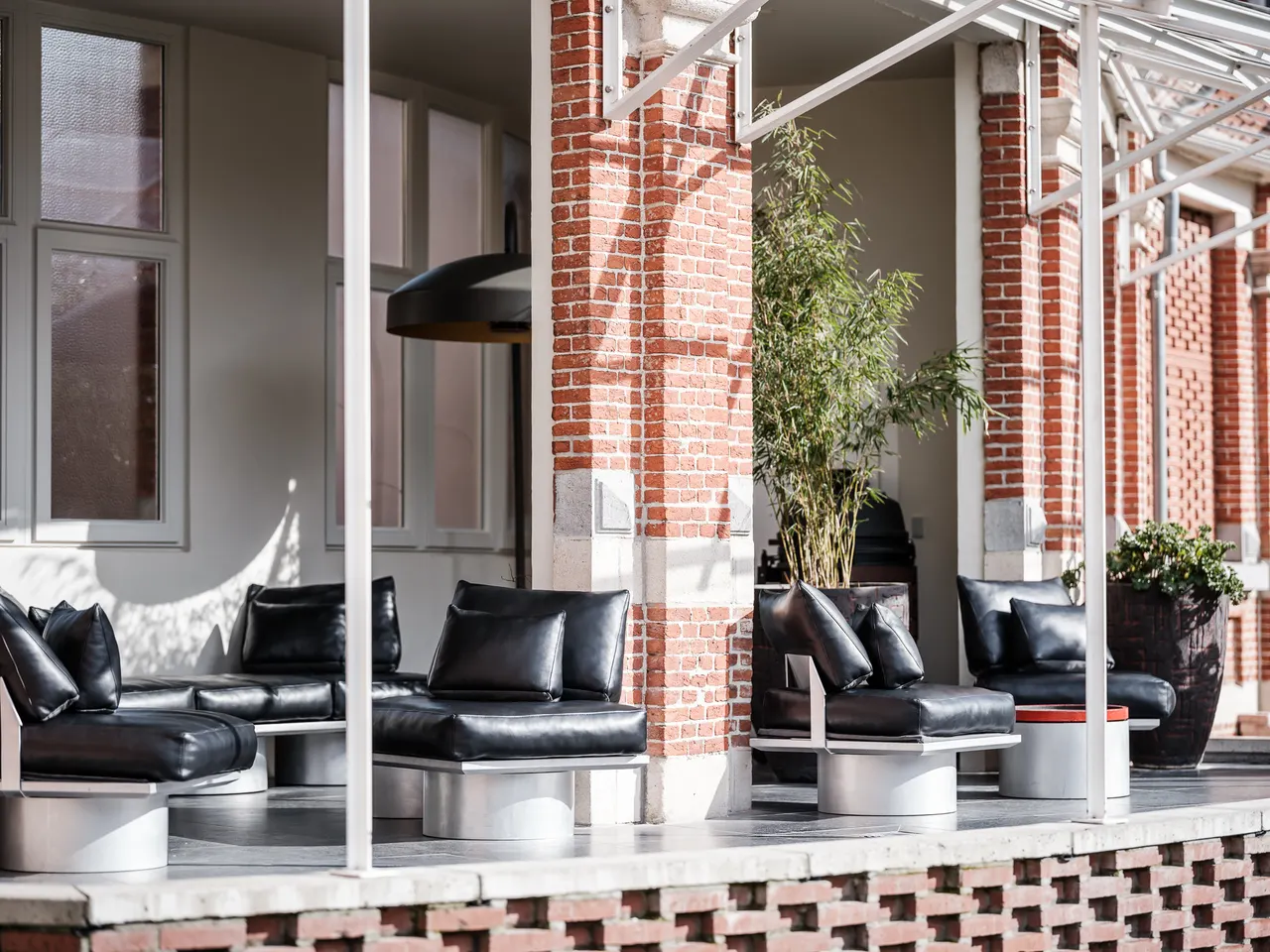 Zetels en bijzettafels uit de reeks Mixture van Studio Bjorn Verlinde onder een bakstenen galerij in Kortrijk