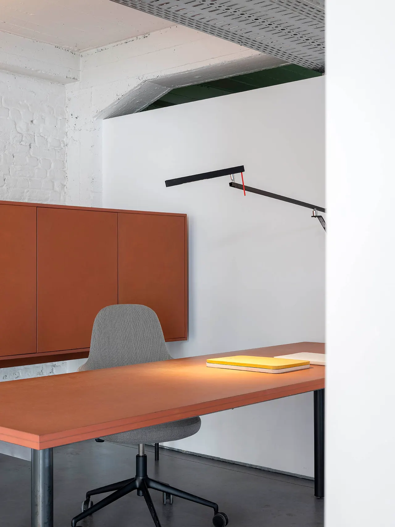 Bureau met gele map en terracotta wandkast