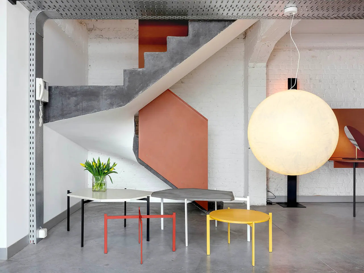 Trap, grote bollamp en gekleurde tafels in de showroom