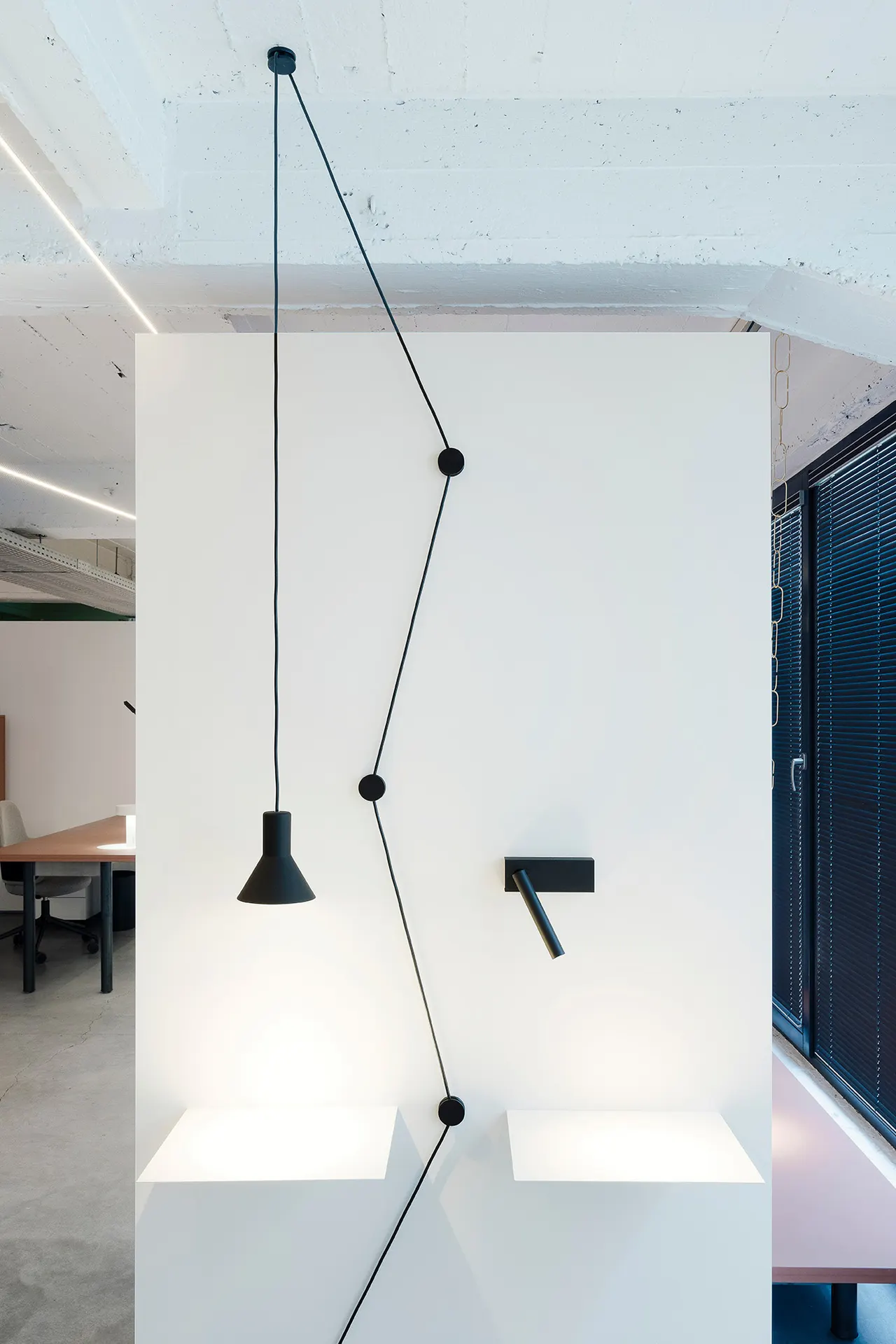Zwarte hanglampen met lange kabels voor een witte wand