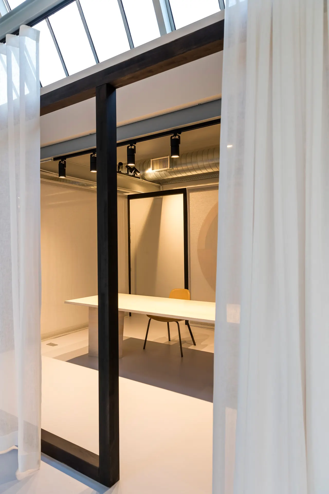 Vergaderruimte achter een zwart kader en linnen gordijn in de showroom van Verilin in Kortrijk