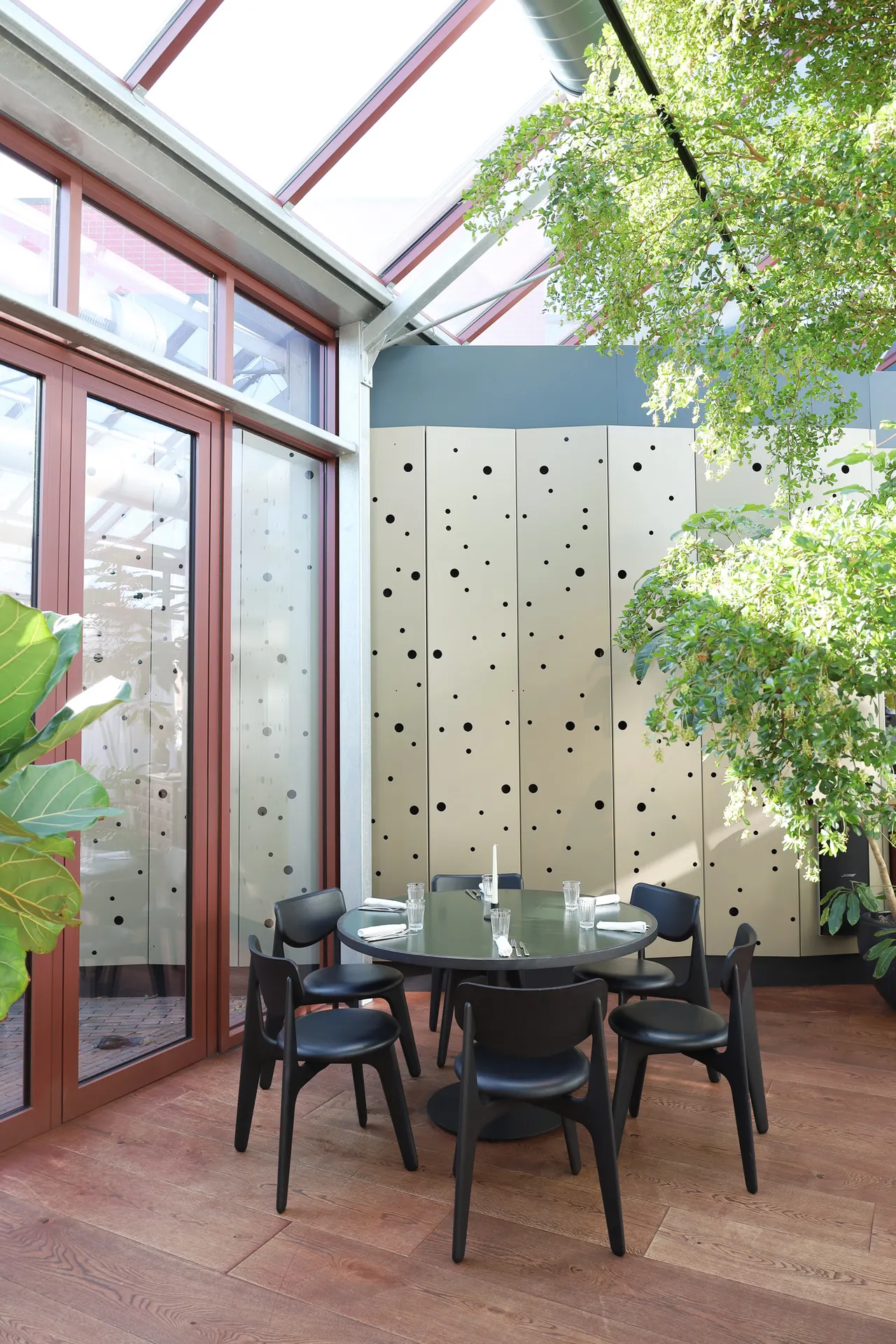 Ronde tafel in de serre met planten en houten ramen