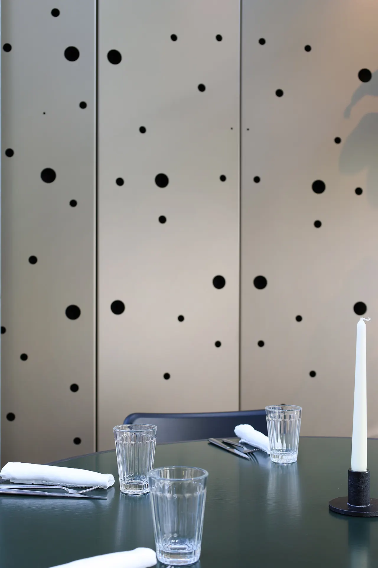 Glazen en kaars op een tafel voor een geperforeerde wand