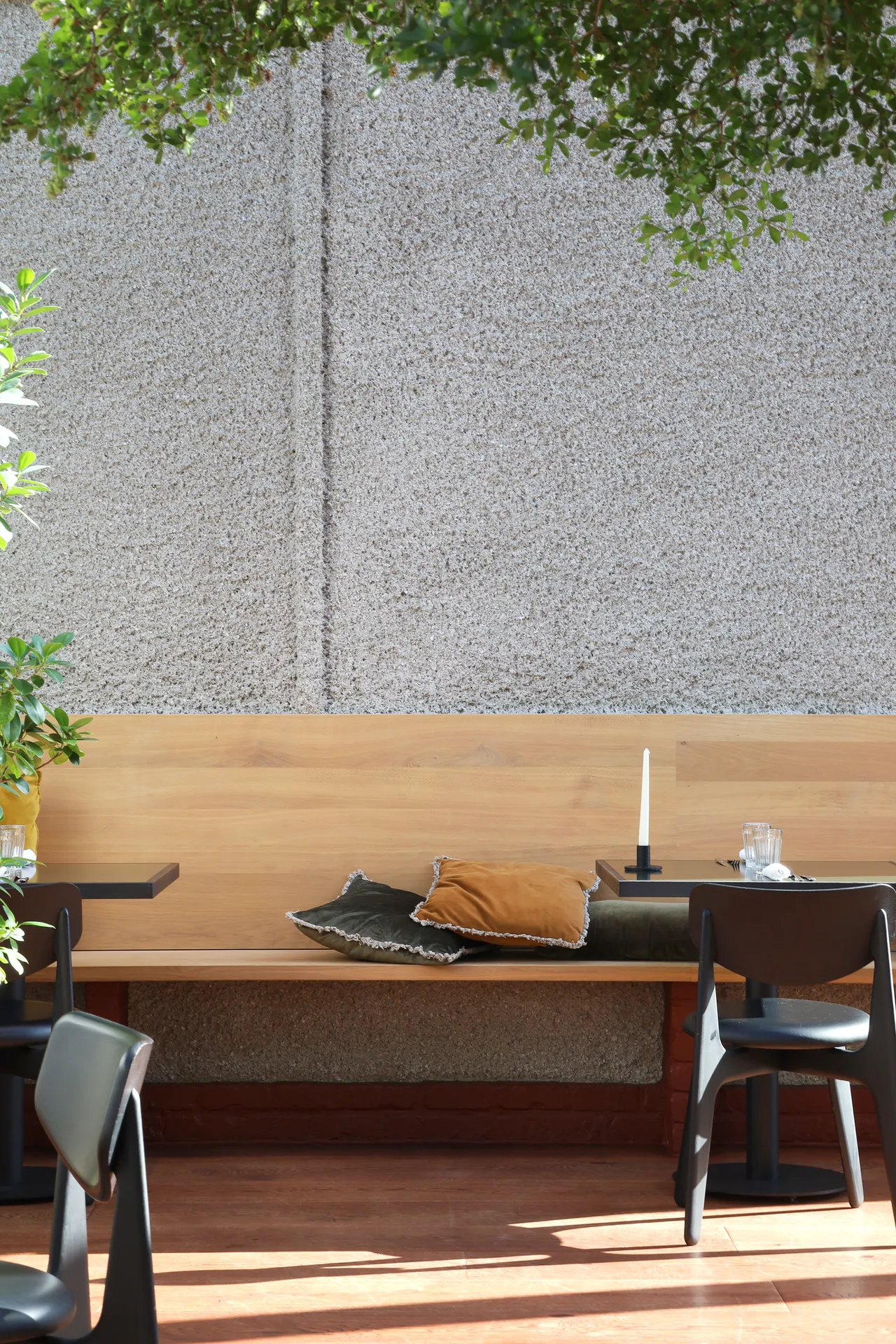 Houten bank en tafel tegen een wand met reliëf onder groen