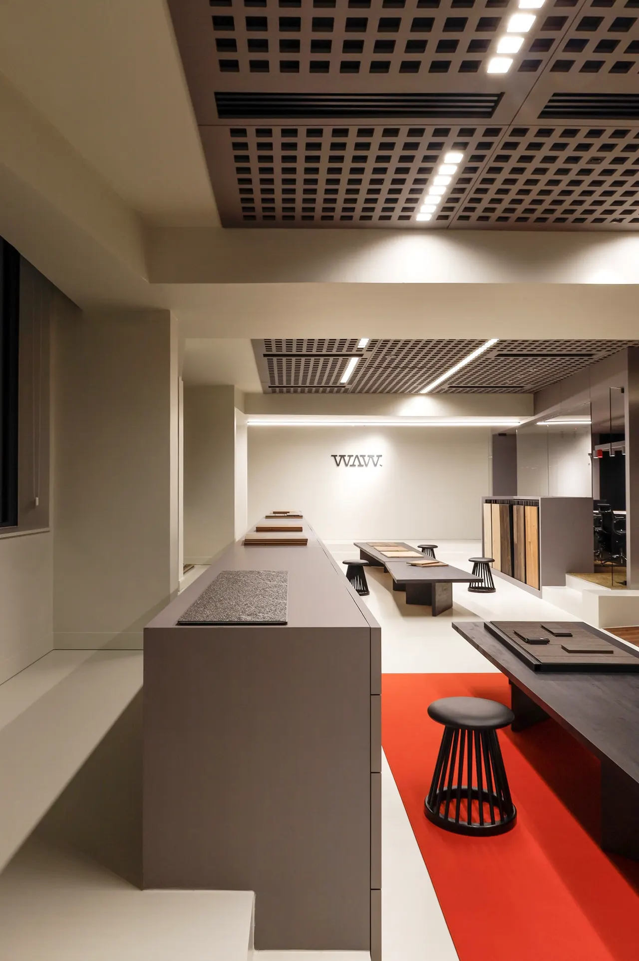 Zicht door de showroom met rode vloerzone en krukken